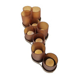 Libra Interiors Hammered Glass 9-Light Amber Lantern with nine amber votive cups at alternating heights on an aged gold corrugated base.