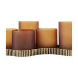 Libra Interiors Hammered Glass 9-Light Amber Lantern shown close-up with amber frosted votives at staggered heights on an aged gold corrugated base.