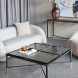 Libra Interiors Textured Glass Square Coffee Table in black with four brick-pattern glass slabs and brass-tipped iron legs, styled in a neutral living room.