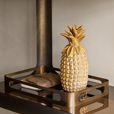 Libra Interiors Smoked Gold Glass Serving Tray in bronze holding a glazed ceramic pineapple and leather-bound notebook, styled beside a wood burner.