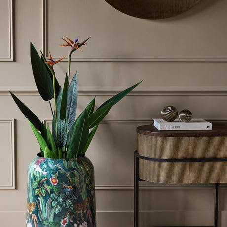 Libra Interiors Glossy Enamel Tropical Iron Vase in blue multicolour with bird of paradise stems, styled in a hallway beside a fluted console table.
