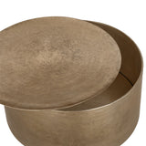 Libra Interiors Drum Storage Coffee Table in champagne gold aluminium with pitted finish, lid lifted to reveal round interior storage compartment.