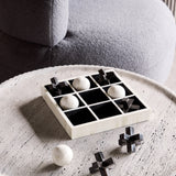 Libra Interiors bone and horn inlay noughts and crosses game with white bone balls and black horn crosses, displayed on a pale round coffee table.