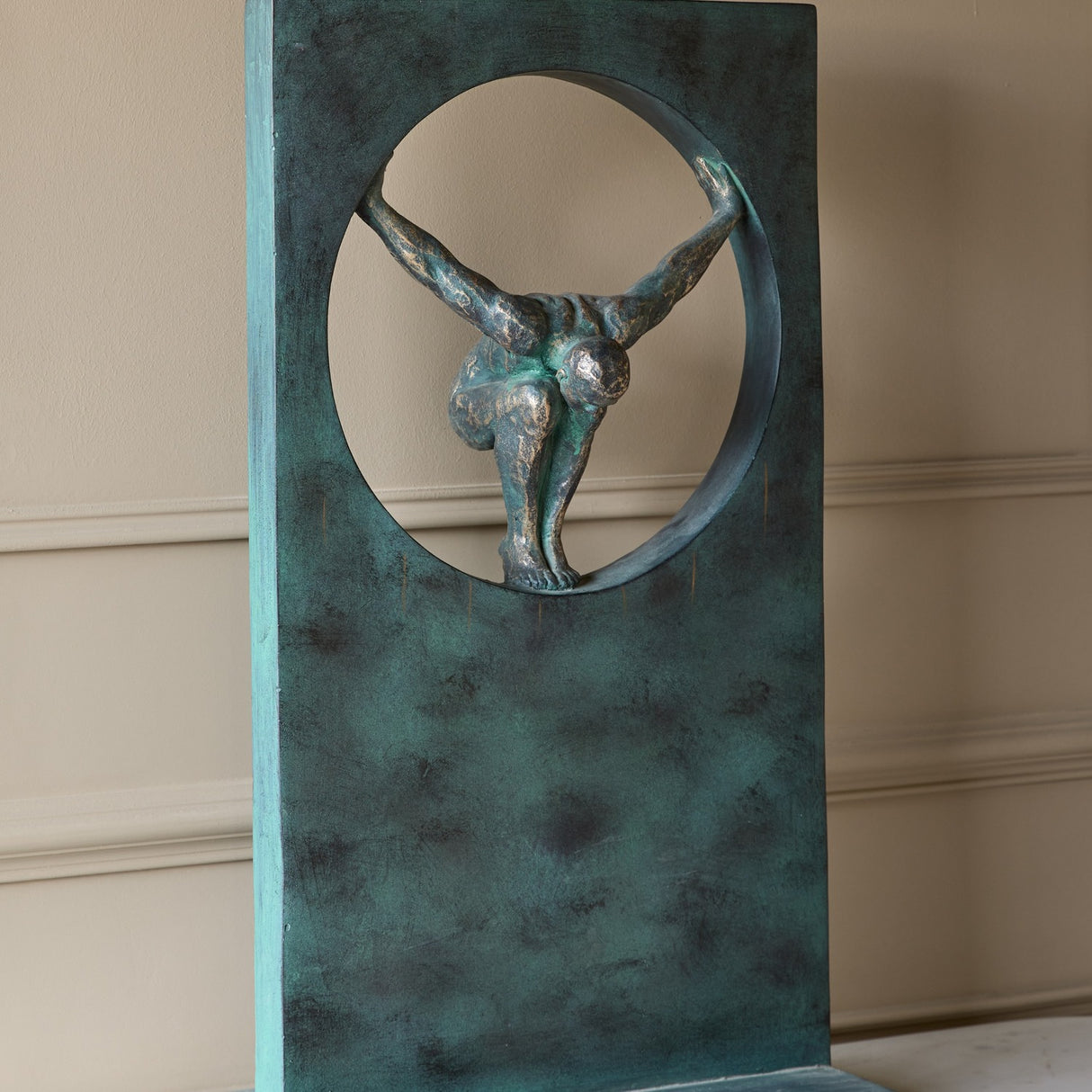 Libra Interiors Verdigris Bronze Framed Diver Sculpture in green, showing the crouched figure poised within the circular cut-out of the tall rectangular frame.