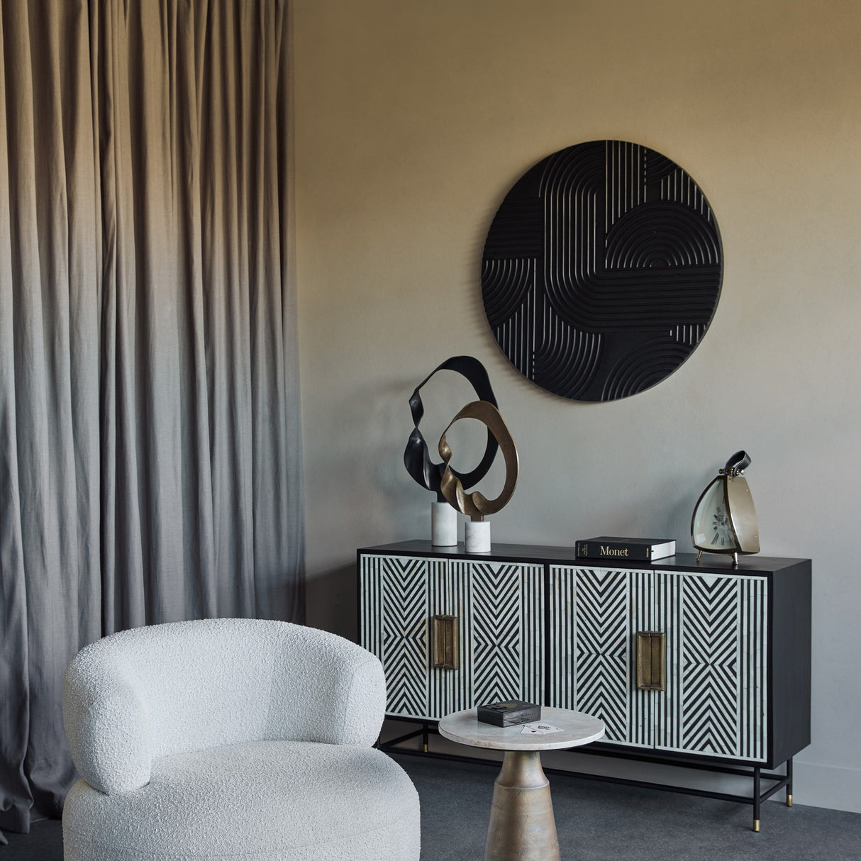 Libra Interiors Looping Abstract sculpture in matt black aluminium on a white marble base, displayed on a patterned sideboard in a modern living room.