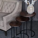 Libra Interiors Radial Etched round nesting side tables in bronze with black frames, staggered beside a grey armchair with a cotton stem vase on top.