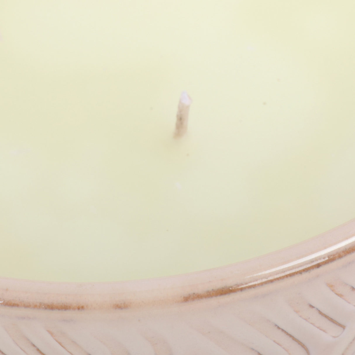 Close-up of Libra Interiors Embossed Glazed Ceramic Bowl Candle in ivory, showing a single wick in pale wax above the glossy embossed geometric rim.