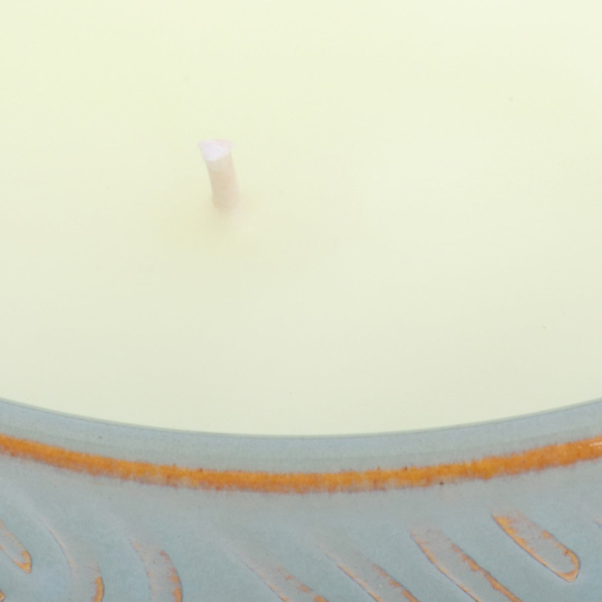 Close-up of the Libra Interiors Embossed Ceramic Bowl Triple-Wick Candle in green, showing pale wax, a central wick and blue-green embossed rim.