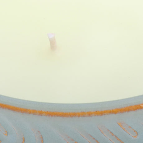 Close-up of the Libra Interiors Embossed Ceramic Bowl Triple-Wick Candle in green, showing pale wax, a central wick and blue-green embossed rim.