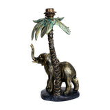Libra Interiors Palm and Elephant resin candle holder in gold, with an elephant beneath a palm tree topped by a taper fitting, on a plain background.