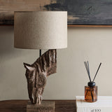 Libra Interiors Sculptural Horse Head resin table lamp in brown with weathered finish and neutral hessian-effect drum shade, styled on a wooden console.