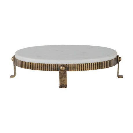 Libra Interiors Marble Oval Aged Gold Cake Stand in white, with a smooth marble top on a corrugated aged gold iron base with splayed feet.
