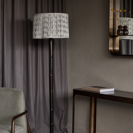 Libra Interiors Bamboo-Effect Ikat Shade Floor Lamp in bronze with pleated grey ikat linen drum shade, styled beside a console table and armchair.