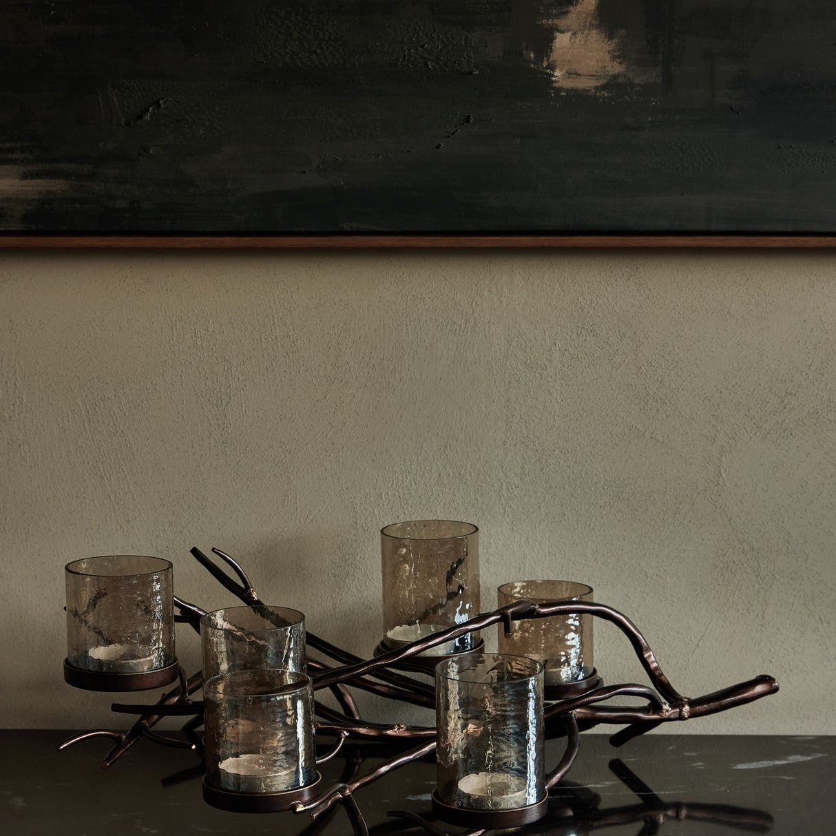 Libra Interiors Branch Design six-light lantern with smoked hammered glass holders on a bronze iron branch frame, styled on a dark console below artwork.