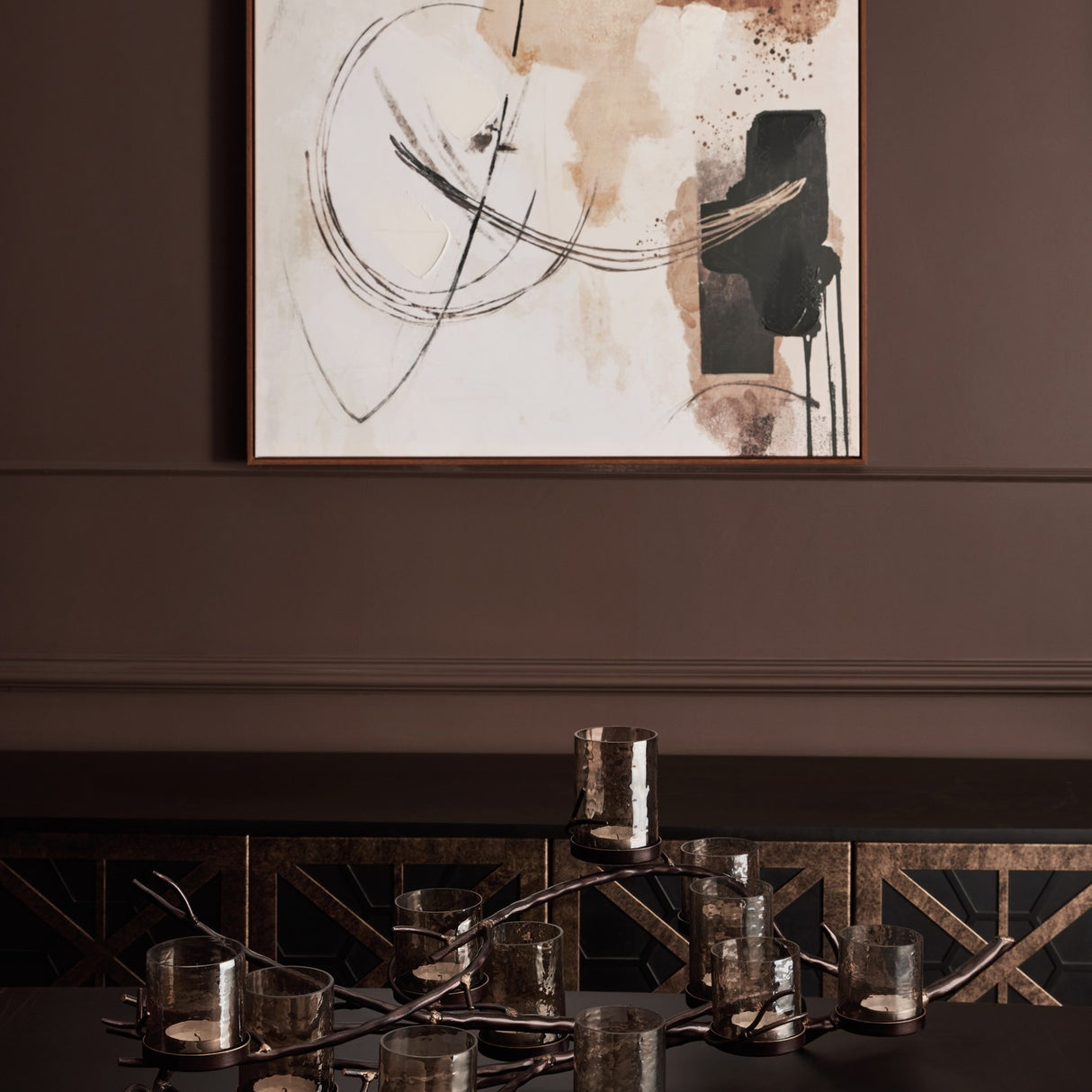 Libra Interiors 11 Light Branch Candelabra in bronze with hammered smoked glass holders on an iron branch frame, styled on a dark console beneath abstract art.
