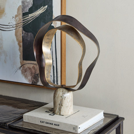 Libra Interiors Marble Base Abstract Ribbon Sculpture in beige and gold, with looping gilded iron ribbons on a polished marble base, styled on a book.