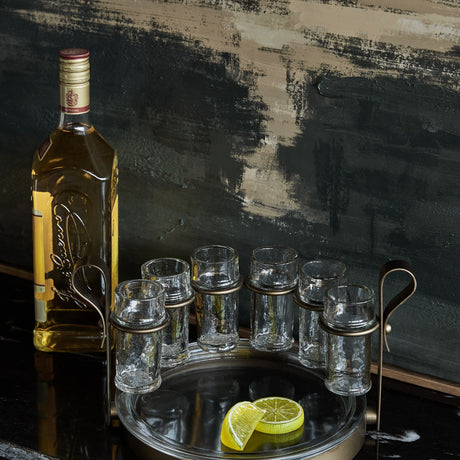 Libra Interiors Hammered Glass 6 Shot Glass Set with six textured glasses in a smoke gold iron frame and tray, styled with a tequila bottle and lime.