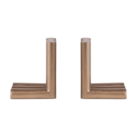 Libra Interiors Ribbed Cast Aluminium Bookends in antique brass, a pair of L-shaped pieces with fluted cylindrical columns, on a plain white background.