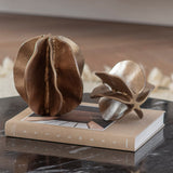 Libra Interiors Petal cast aluminium sculptures in antique brass, layered petal forms styled with a smaller companion piece on a book atop a marble surface.