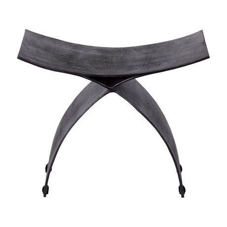 Libra Interiors Cast Aluminium Curved Stool in black, with arched crossed legs and a concave seat in raw textured finish, on a white background.