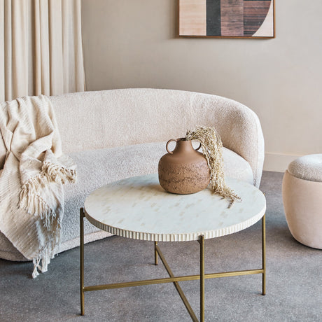 Libra Interiors Bone Inlay Round Brass Coffee Table in white with fluted edge and gold legs, styled in a neutral living room with bouclé sofa and vase.