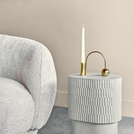 Libra Interiors Tiered Bone Inlay oval side table in cream beside a bouclé armchair, styled with a brass candle holder and taper candle.