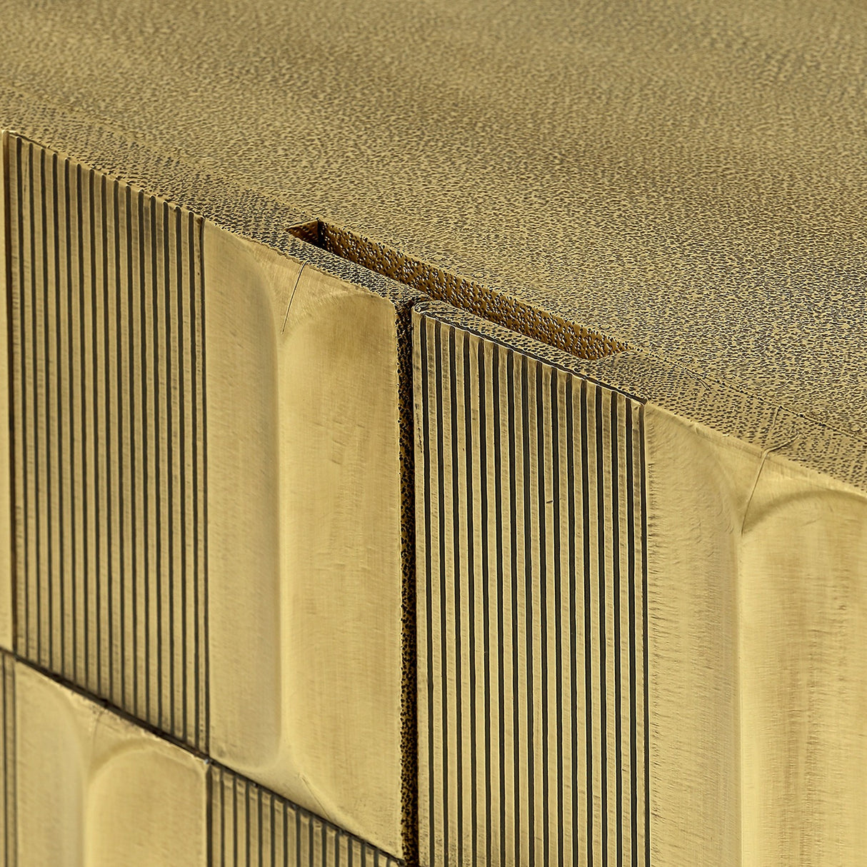 Close-up of Libra Interiors Sculpted Brass Large Sideboard showing the antique brass tiled front with vertical ridges and shagreen-textured top surface.