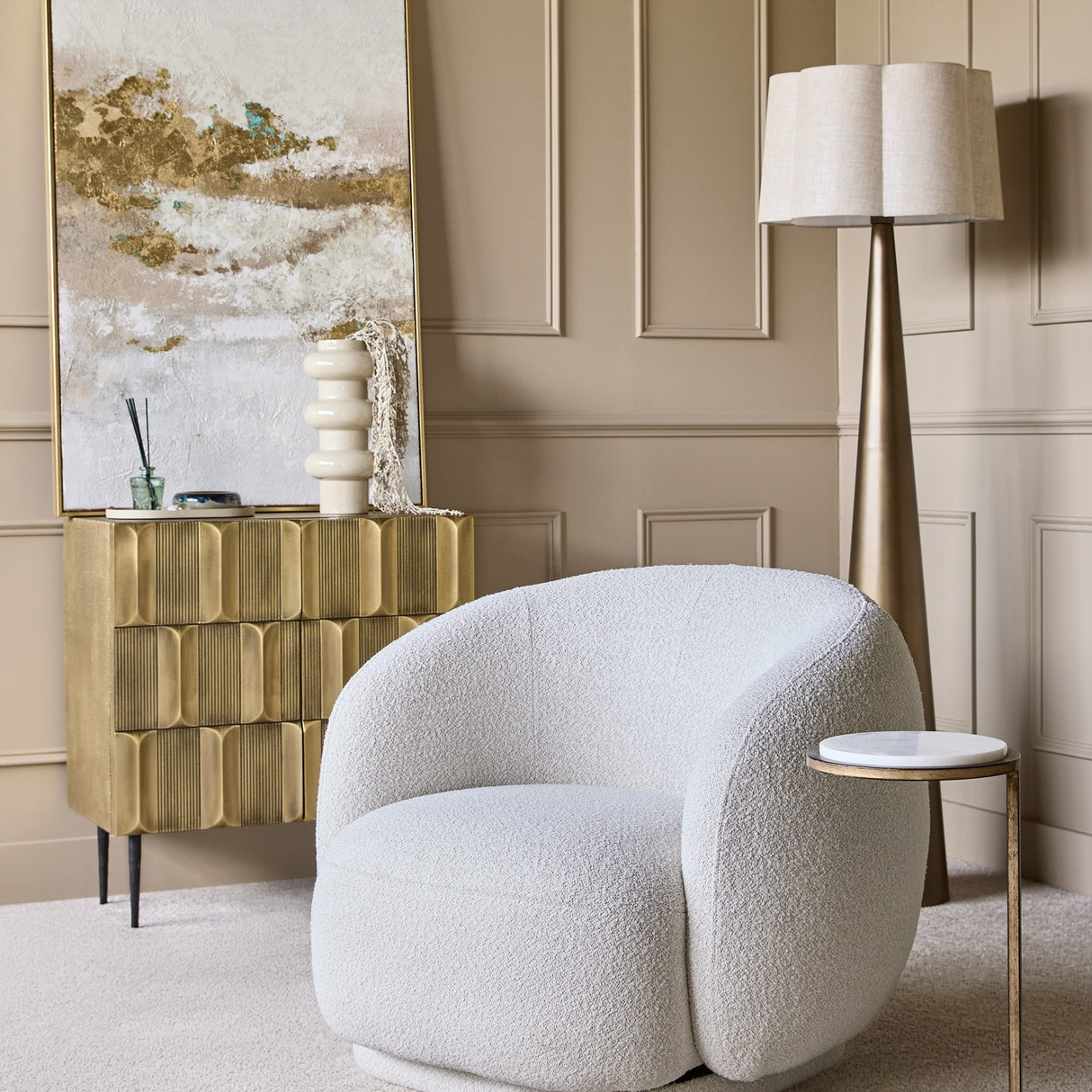 Libra Interiors Textured Brass 2 Door Cabinet in antique brass styled in a panelled living room with a bouclé chair, floor lamp and abstract artwork.