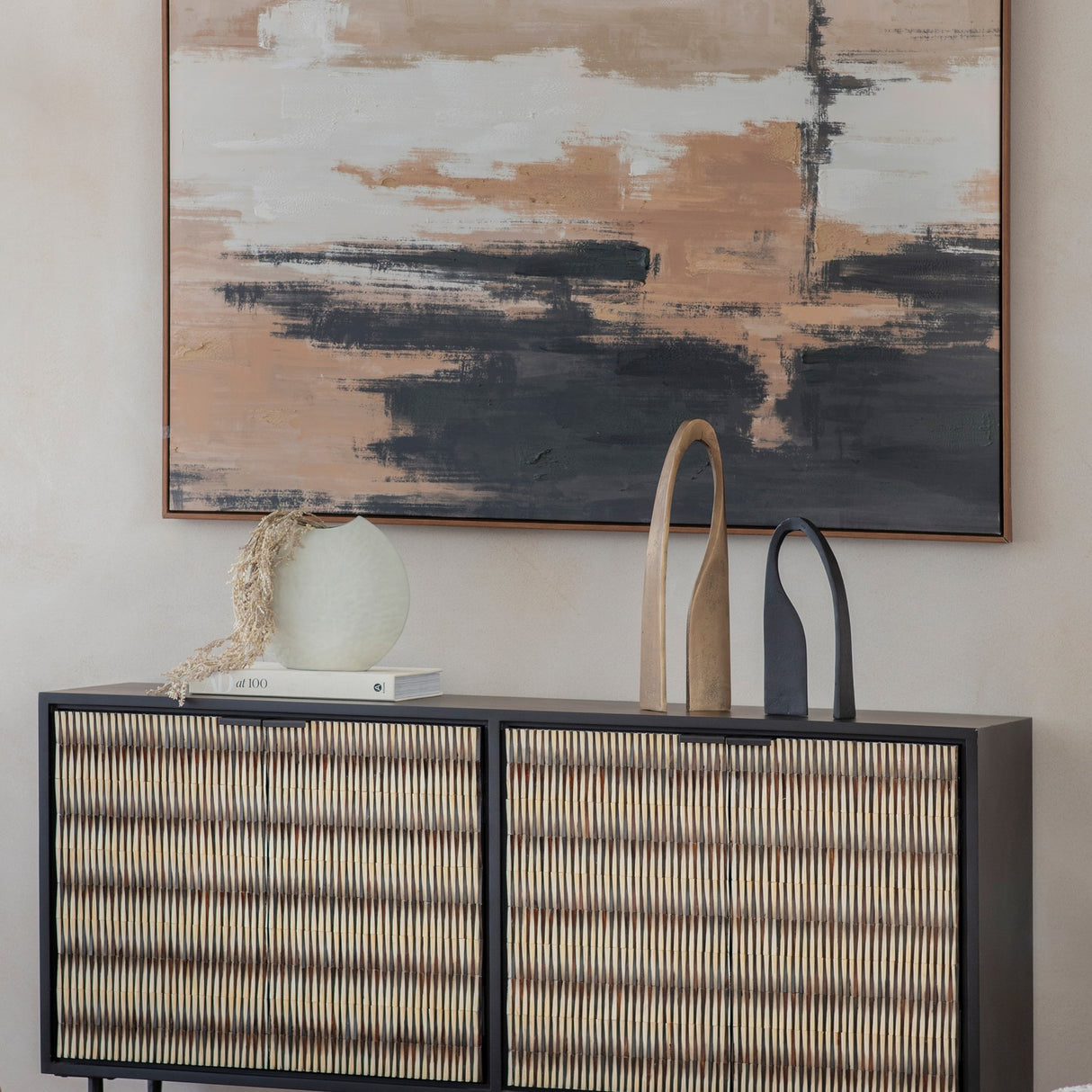 Libra Interiors Bone Inlay sideboard with black frame and ivory raised-pattern doors, styled with a vase, sculptures and book beneath abstract art.