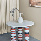 Libra Interiors Bone Inlay Round Dining Table with cream top and three legs in terracotta, black, ivory and grey stripes, styled with a white vase.