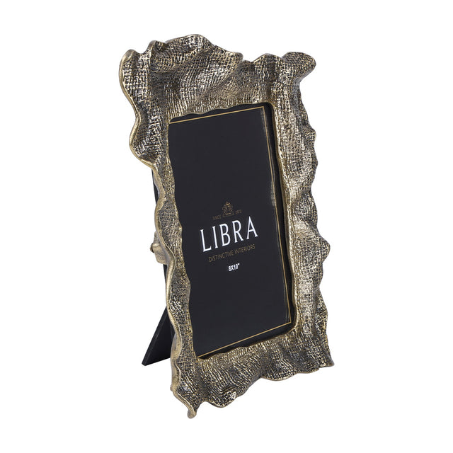 Libra Interiors woven-effect cast aluminium 8x10" portrait photo frame in antique brass with rippled organic edges and fold-out stand, on a white background.