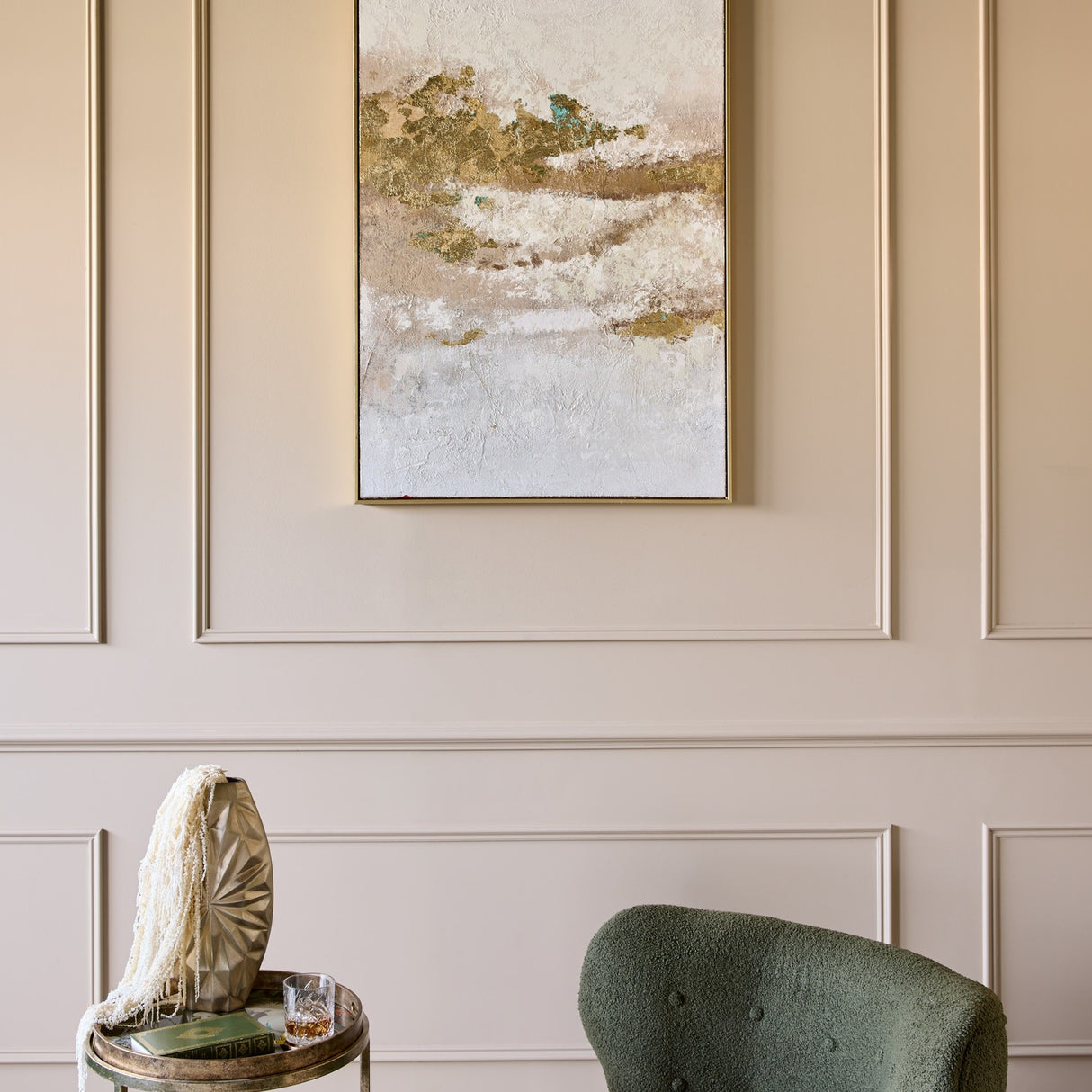 Libra Interiors Heavy Textured Gold Abstract Canvas Wall Art in a slim gold frame, displayed on a cream panelled wall above a green chair and side table.