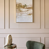 Libra Interiors Heavy Textured Gold Abstract Canvas Wall Art in a slim gold frame, displayed on a cream panelled wall above a green chair and side table.