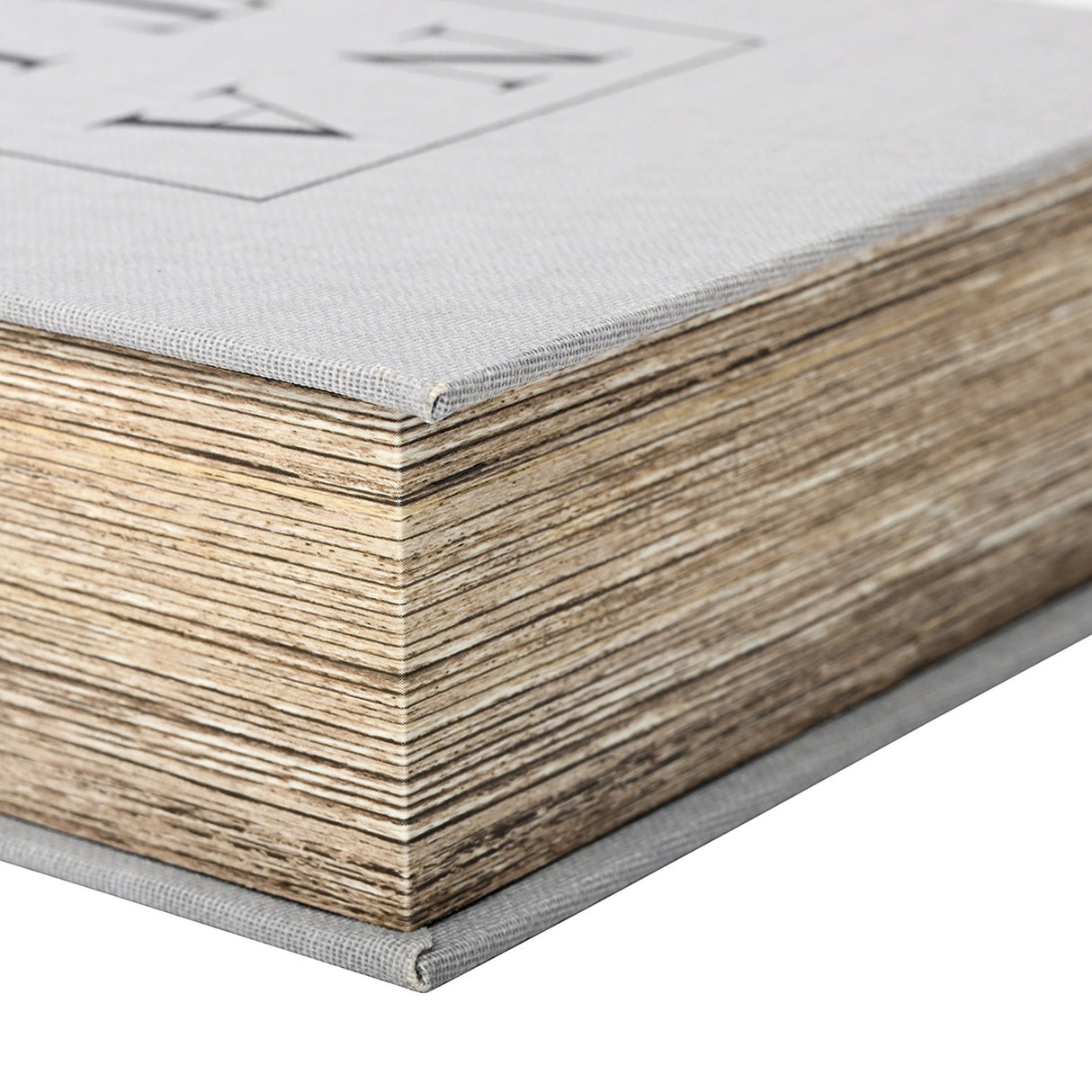 Close-up corner detail of the Libra Interiors Linen Book-Style Storage Box in white, showing pale grey linen binding and textured wood-effect page edges.