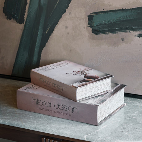 Libra Interiors Faux Leather Book Storage Boxes stacked on a marble console, printed "interior design natural elements" covers in neutral tones.