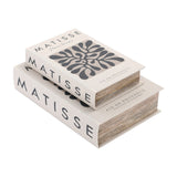 Libra Interiors Matisse linen book-style storage boxes in white with charcoal typography and abstract cut-out motif, stacked on a plain background.