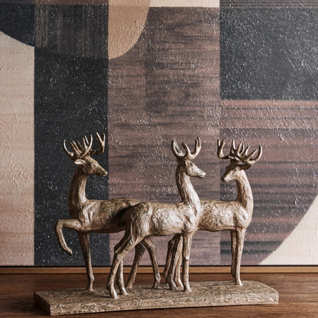 Libra Interiors Textured Trio of Stags Sculpture in brown resin with antlered figures on a shared base, styled on a wooden surface against abstract art.
