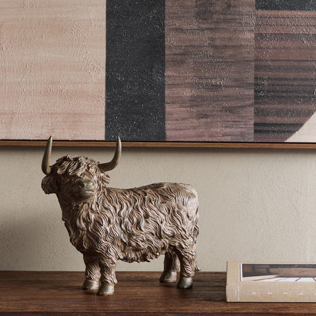 Libra Interiors Rustic Textured Highland Cow Sculpture in brown resin, styled on a wooden console beneath abstract art with a book alongside.