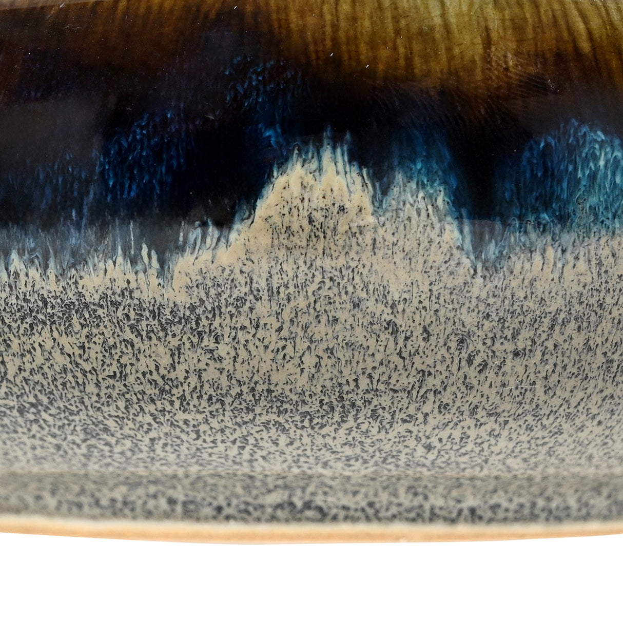 Close-up of the Libra Interiors Reactive Glaze Stoneware Bowl in blue, showing the pooled inky blue, amber and mottled grey glaze across the ceramic side.
