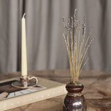 Libra Interiors Reactive Glaze Gourd Stoneware Vase in speckled brown with gold flecks, holding dried lavender stems beside a taper candle and book.