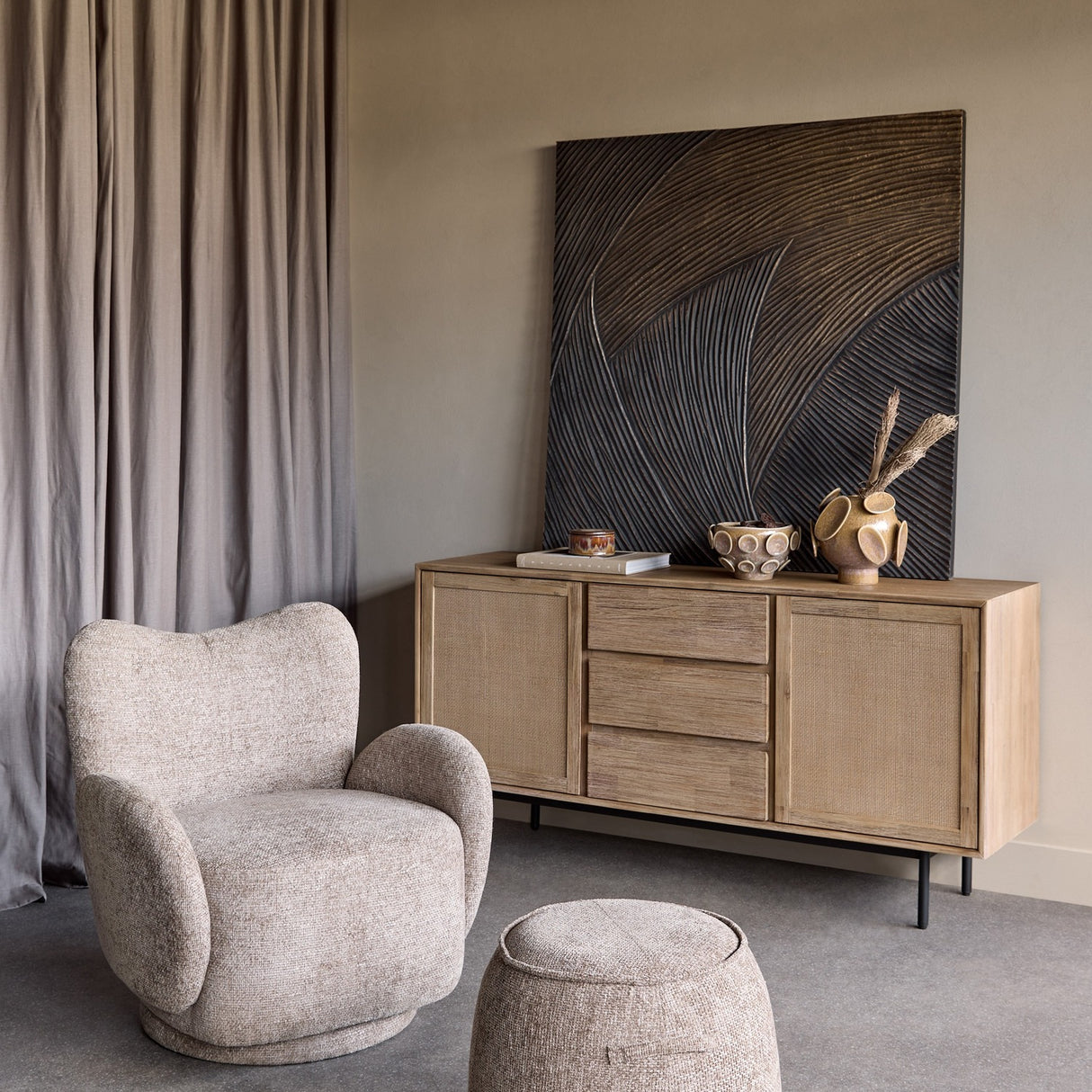 Libra Interiors Reactive Glaze stoneware planter in mottled brown with raised circular motifs, styled on a wood sideboard beside a carved wall panel.