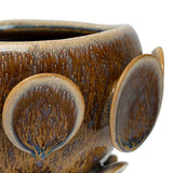 Close-up of Libra Interiors Reactive Glaze Raised Circle stoneware planter in mottled brown, showing raised circular discs and glossy tonal glaze detail.