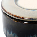 Close-up of Libra Interiors Reactive Glaze Ceramic Rose Candle in blue, showing the glossy inky body and cream-toned lid with rich amber rim detail.