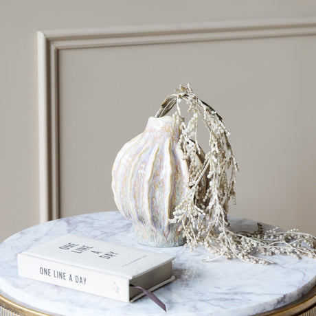 Libra Interiors Textured Reactive Glaze Ceramic Vase in cream with ribbed sculptural body, holding dried stems on a marble table beside a journal.