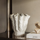 Libra Interiors Ruffled Ceramic Wavy Vase in cream with glossy reactive glaze and golden-brown speckled rim, styled on a dark console with books.