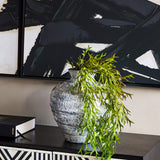 Libra Interiors Textured Glaze Wash ceramic vase in white with a trailing green fern, styled on a dark console beneath bold black brushstroke artwork.
