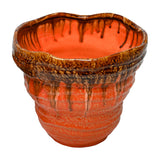 Libra Interiors Reactive Glaze Ceramic Planter in orange with brown drip glaze rim, ridged textured body and rounded shape, on a white background.