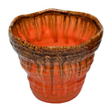 Libra Interiors Reactive Glaze ceramic planter with wavy rim, textured body and glossy brown drips over warm orange, shown on a white background.