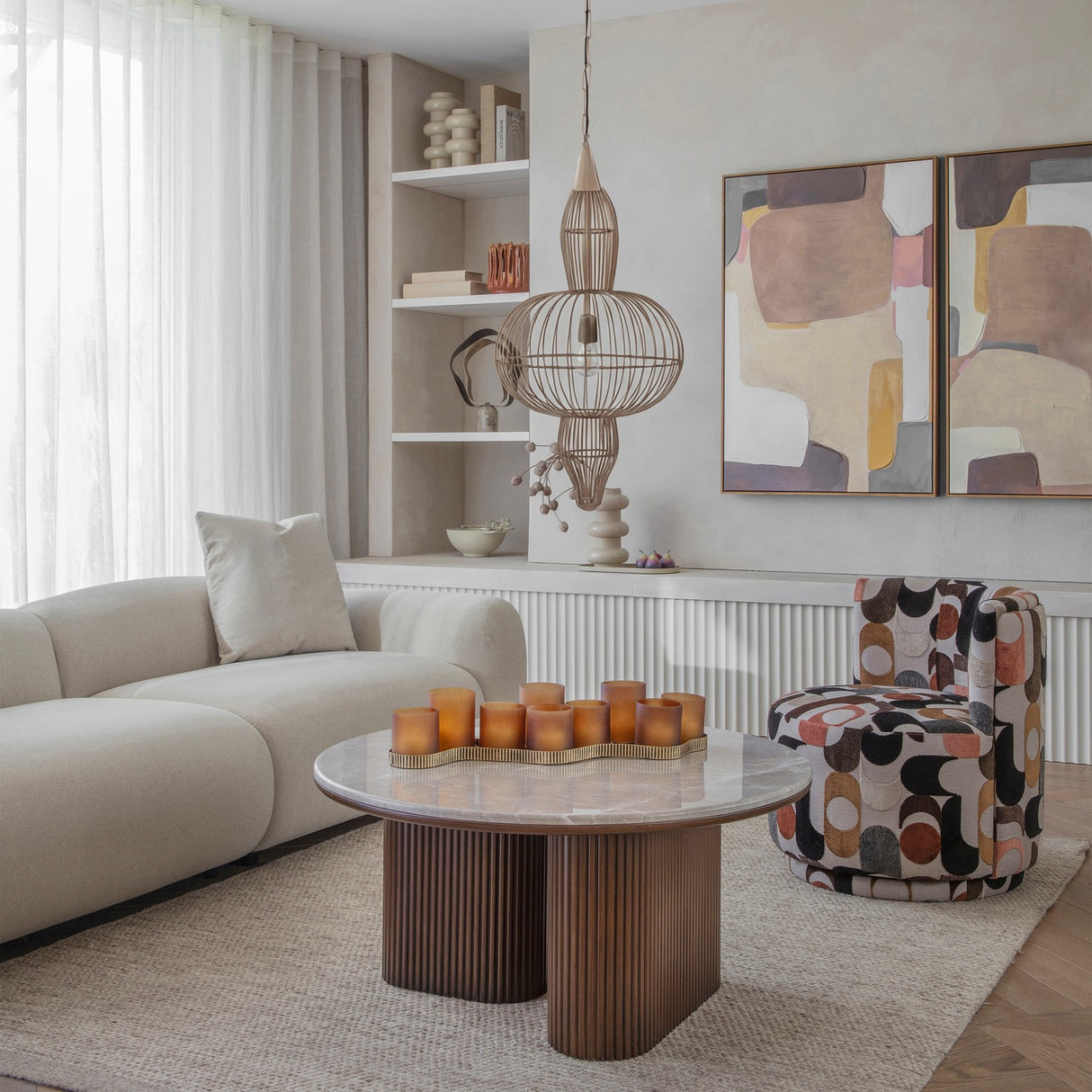 Libra Interiors Wire Frame Burnished Brass Pendant Light with three-tier caged silhouette above a marble coffee table in a neutral living room.