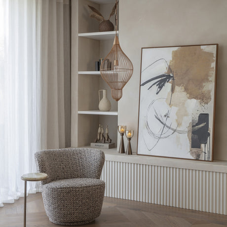 Libra Interiors Teardrop Wire burnished brass pendant light hanging beside open shelving in a neutral living room with a bouclé armchair and abstract artwork.